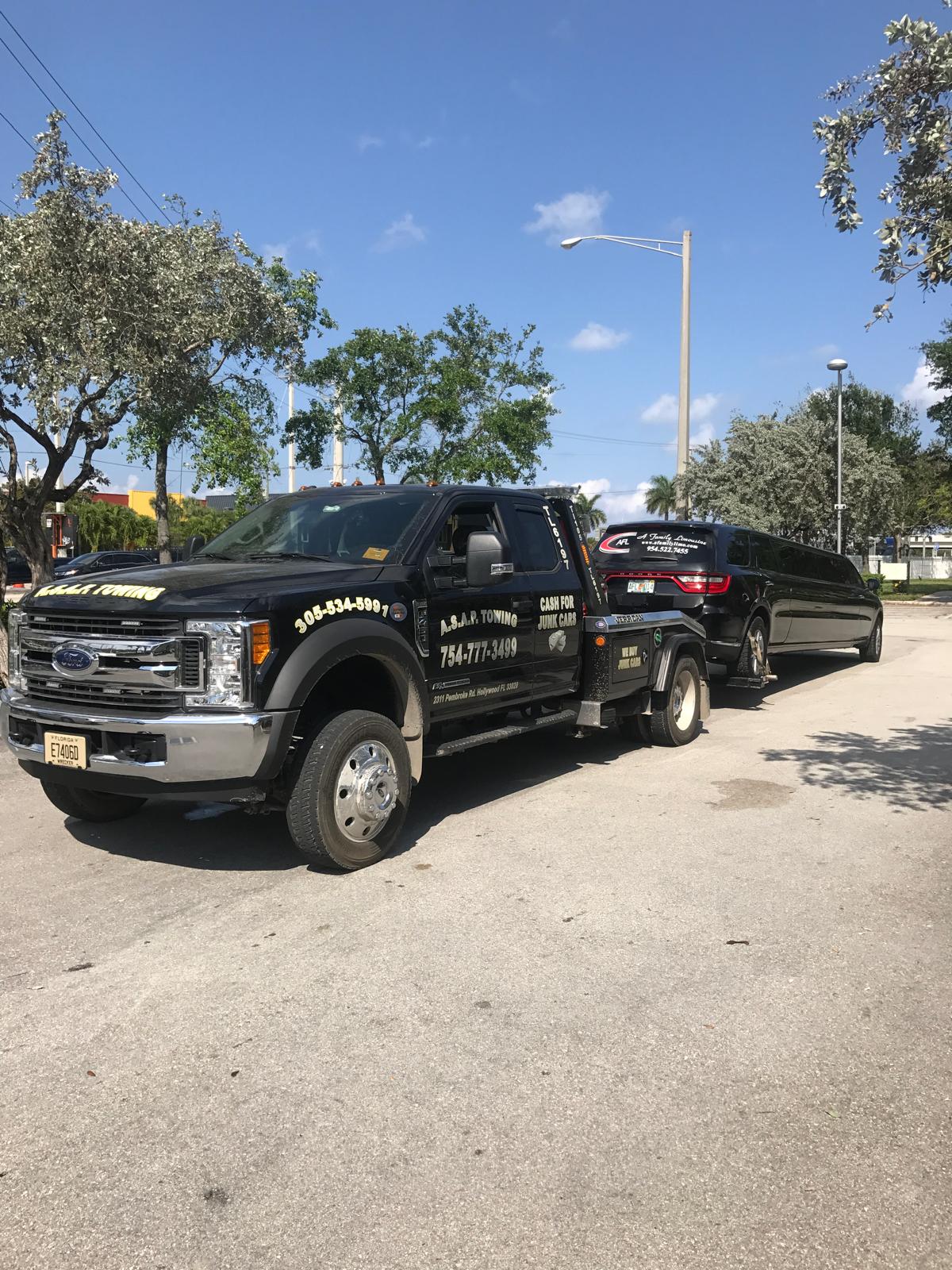 Towing truck hauling a junk car away.